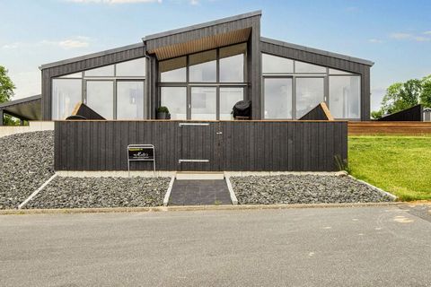 Ce fantastique cottage avec bain à remous et vue panoramique sur la mer à Skarrev offre un emplacement et des installations d'une classe à part. Le chalet apparaît en même temps comme une solution architecturale très agréable avec le côté le plus lon...